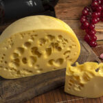 closeup-shot-block-gourmet-swiss-cheese-wooden-board_181624-38491